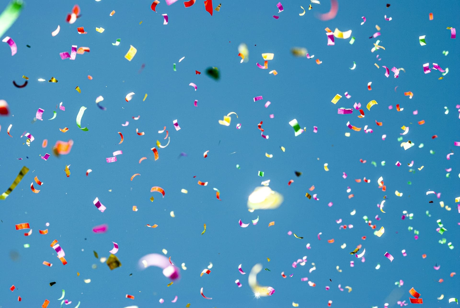 Colorful confetti falling through a blue sky